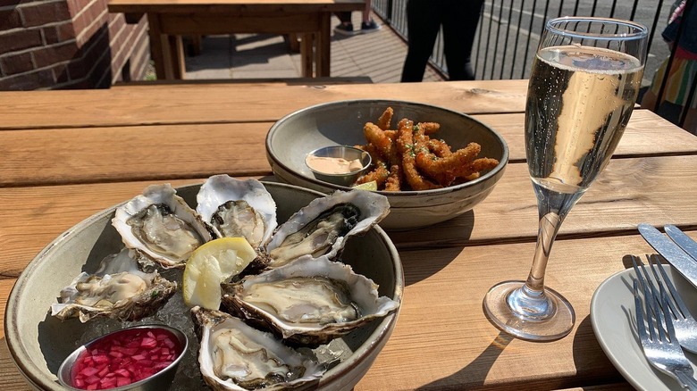 A bowl of oysters on ice and a glass of bubbly outside The Oyster Smack Inn in Burnham-on-Crouch