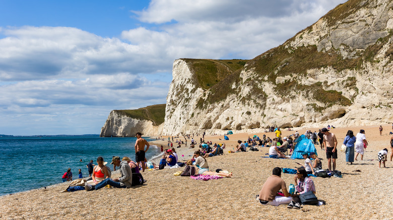 People sunbathe on the sands of Durdle Door beach in the summer
