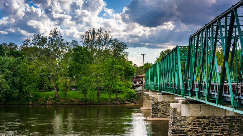 A green metal bridge resting on stone piers in the water in Belvidere, New Nersey