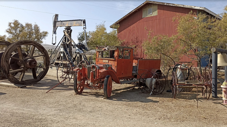 Antique oil field equipment in front of a barn at West Kern Oil Museum.