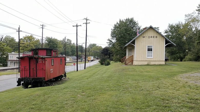 Red Caboose and main historic depot building on cloudy day