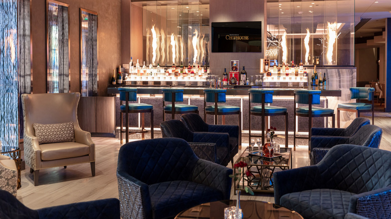 The lounge and bar area at Monarch Chophouse, a sleek, clubby space with dark woods and velvet chairs