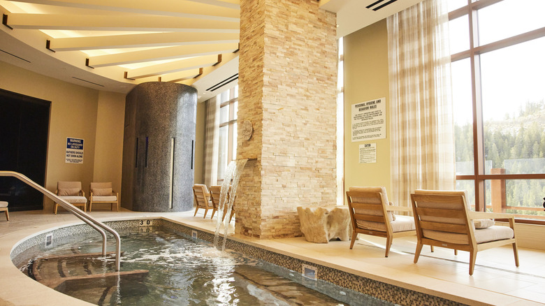 The Monarch Spa Aqua Lounge, a half-sphere jacuzzi with waterfall that overlooks a wall of windows with the mountains beyond