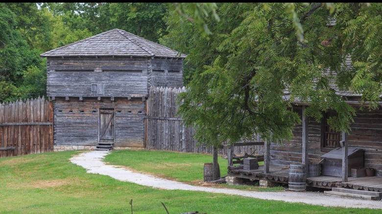 Wooden palisade fence and watchtower surrounded by trees with a path to the door at Fort Osage National Historic Site in Sibley, Missouri