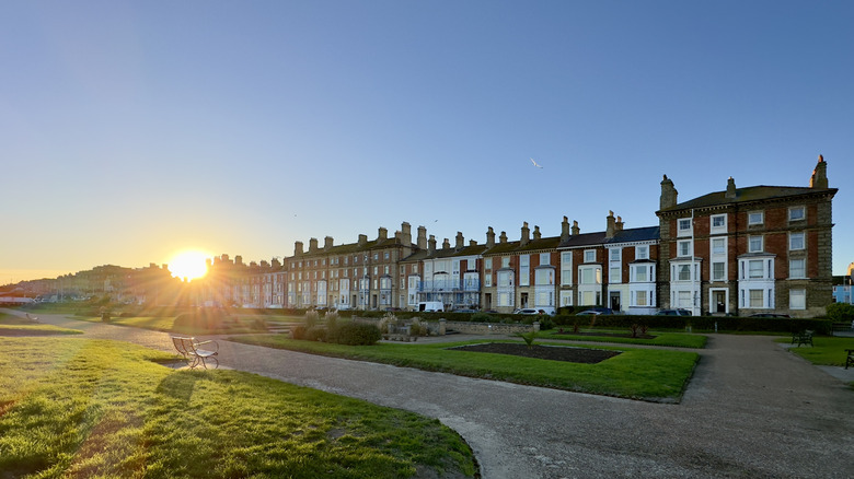 The sun setting behind a row of residential buildings across seafront gardens in Lowestoft, Suffolk, UK
