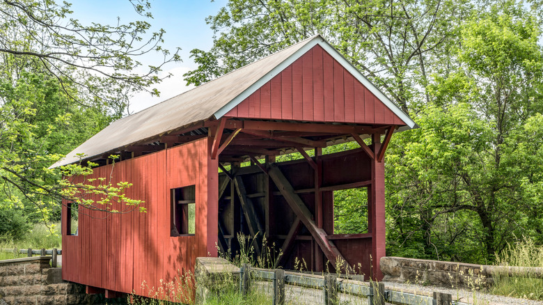 The historic red Erskine Covered Bridge crosses Middle Wheeling Creek in rural wooded Washington County, Pennsylvania