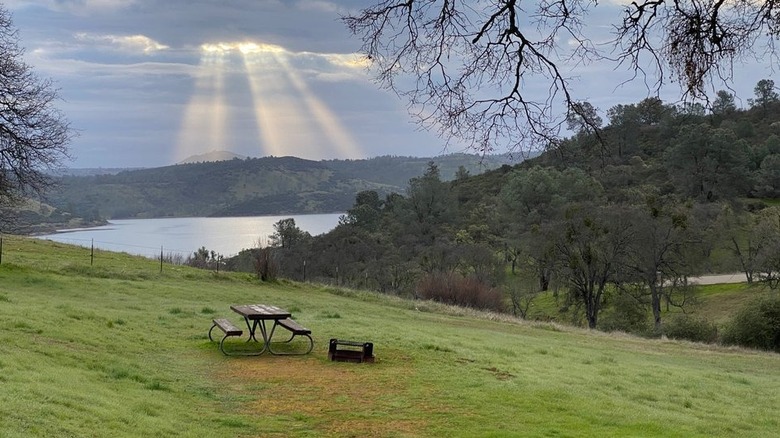 The sun's rays peak through the clouds above Pardee Lake in the Sierra Nevadas.