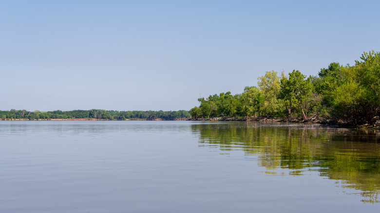 Calm waters of Council Grove Lake, Kansas, with the surrounding greenery reflected on the surface