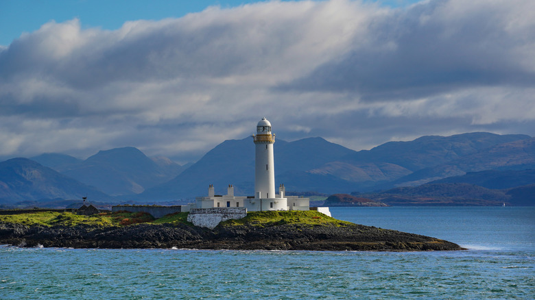 Lismore Lighthouse with mountains in the background, located on the small island Lismore in Scotland