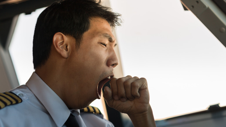 A pilot yawning while sitting in the cockpit