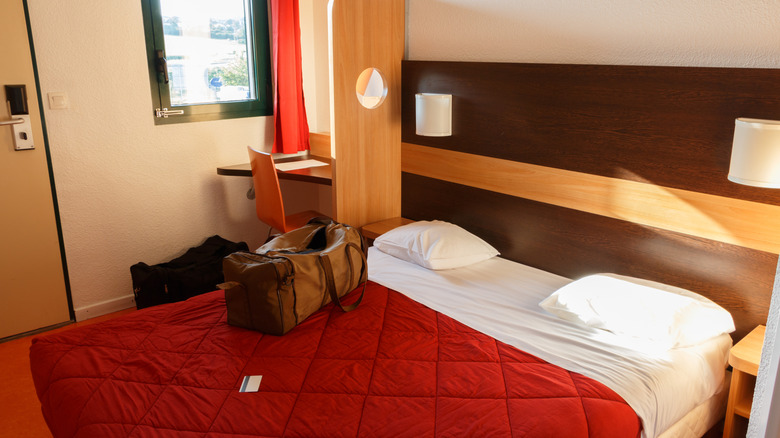 Small budget hotel room with a duffle bag on the bed
