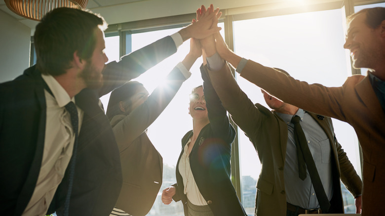 People celebrating with high fives in a professional setting