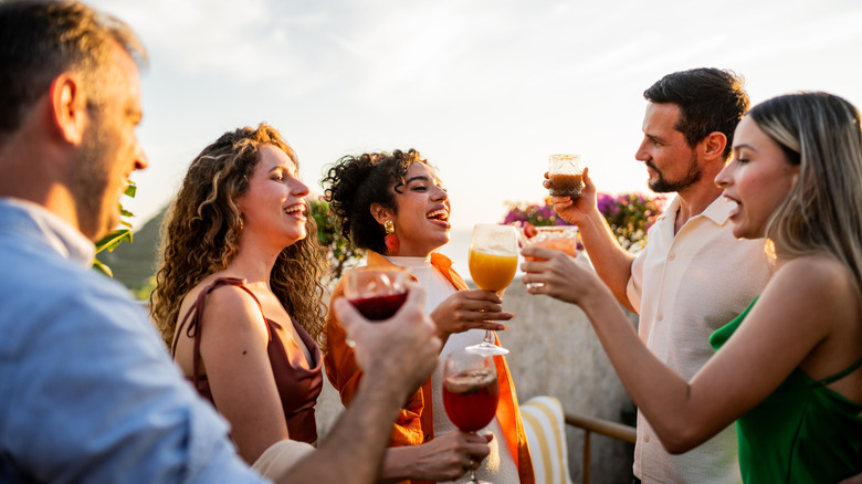 A group of people having cocktails and talking with one woman seemingly talking louder than the others