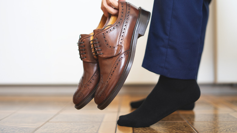A businessman taking off his brown shoes