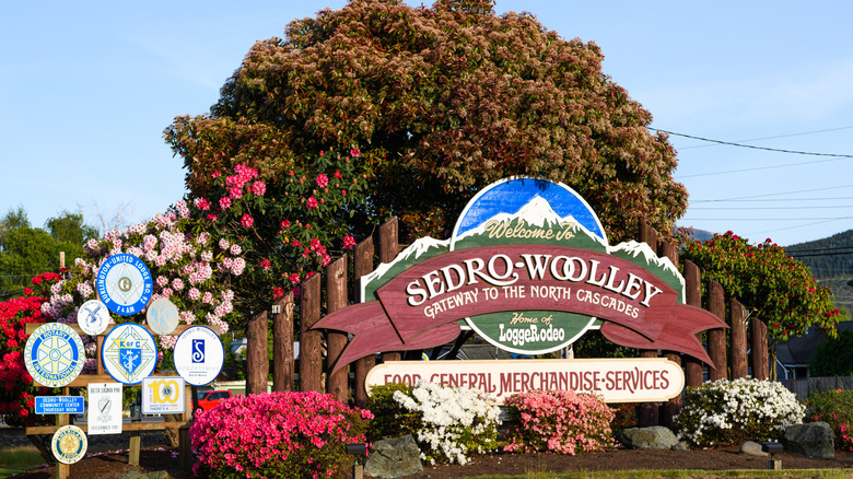 welcome sign for Sedro-Woolley with tree and blooming flowers in background