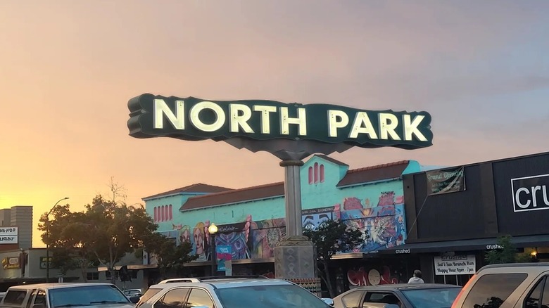 This is a picture of the North Park neighborhood sign with cars and a sunset