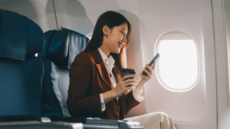 Woman looking at her phone while sitting on an airplane
