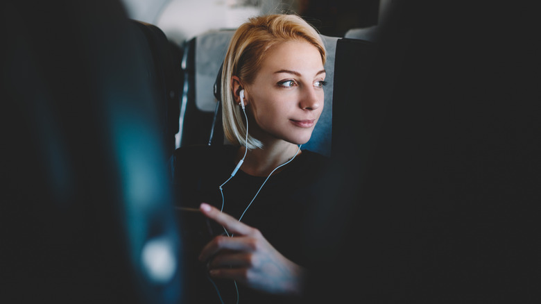 Woman using earphones with her phone during a flight