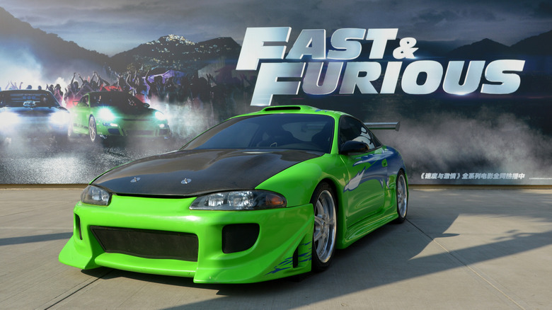 Green car in front of Fast and Furious banner
