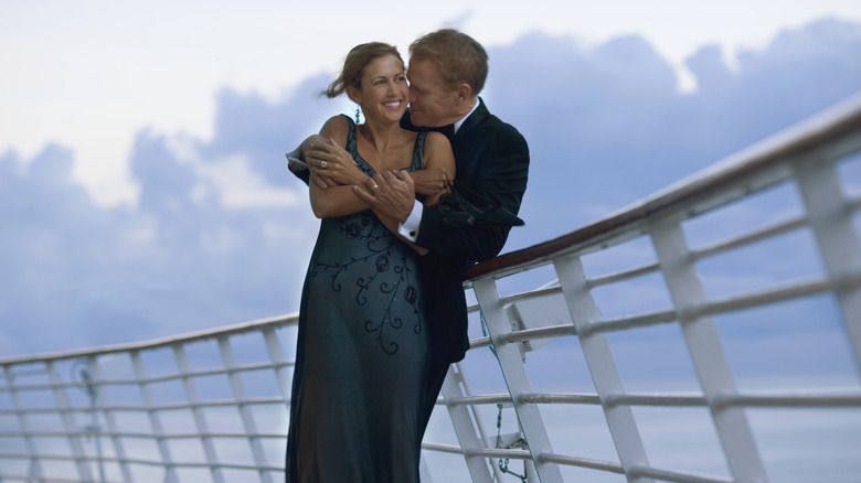 A couple dressed nicely embracing on the rails of a cruise ship