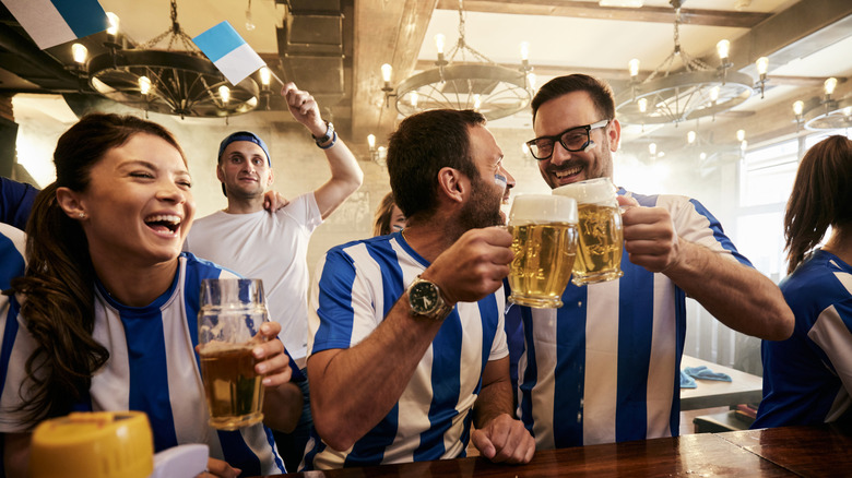 Beer-drinking fans wearing blue and white striped strips in a pub