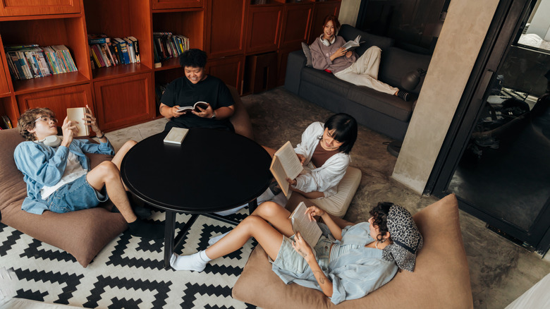 Group of young people sitting around table in hostel common area