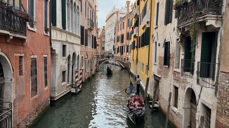 View of a side canal in Venice with a bridge and gondolier visible