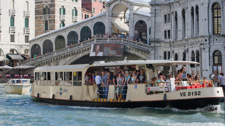 A heavily crowed vaporetto sails the Grand Canal near Rialto Bridge
