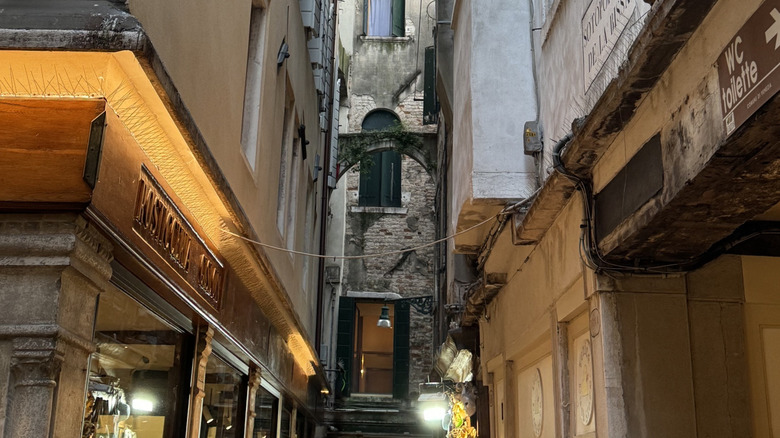 View of an extremely narrow calle wallkway in Venice, Italy, with shops on each side