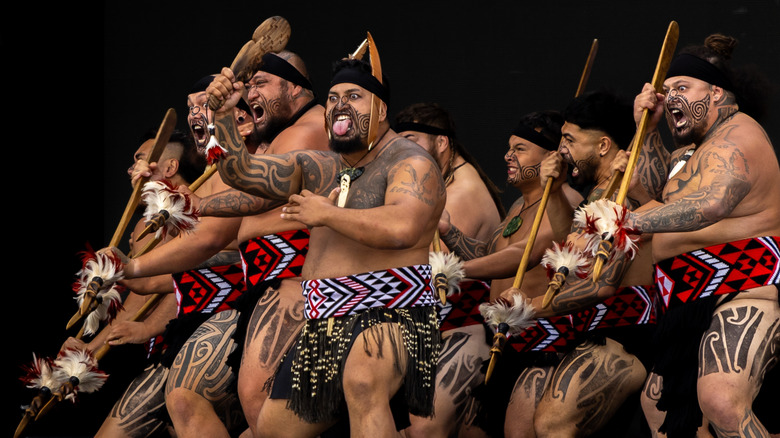 Māori warriors perform kapa haka with taiaha at Rotorua lakefront in New Zealand