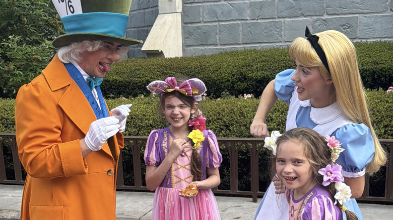 Children enjoying an interaction with roaming Mad Hatter and Alice characters at Magic Kingdom Park in Orlando