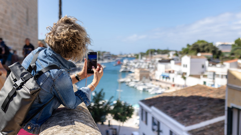 Senior woman in a denim jacket clicking pictures on her phone