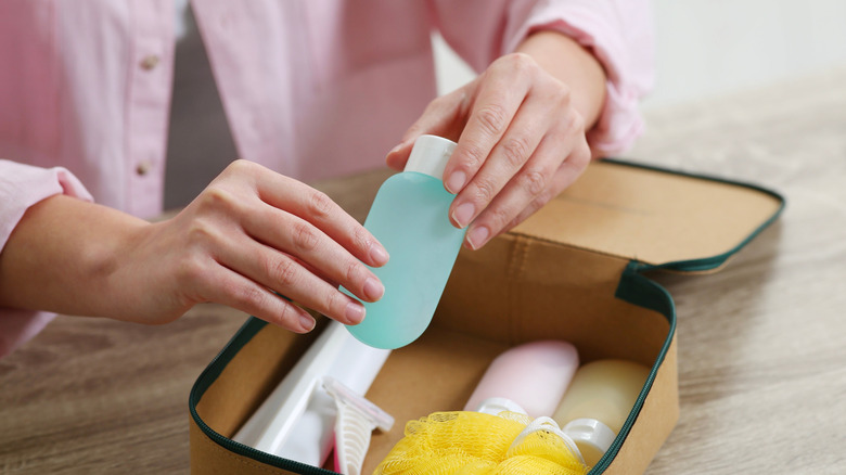 Person in pink shirt placing travel-sized containers in a packing cube