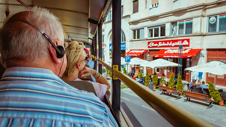 Back shot of an elderly man with an audio headset on a tour bus