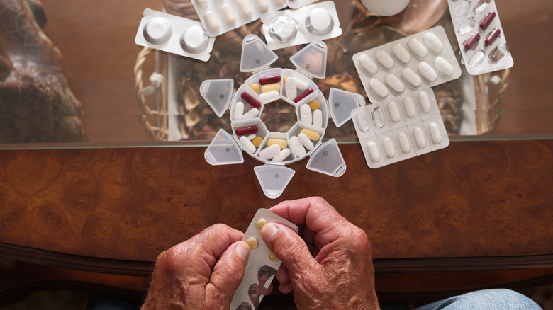 Top shot of elderly person's hands organizing medicine tablets