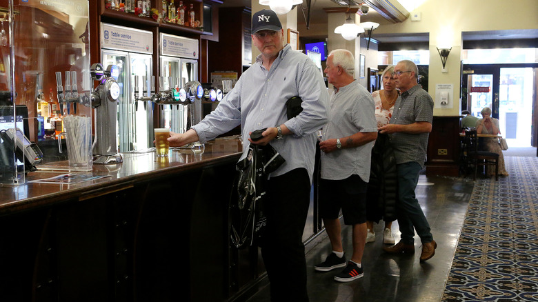People queue to be served at the bar at Wetherspoons pub The Moon Under Water in Manchester, England