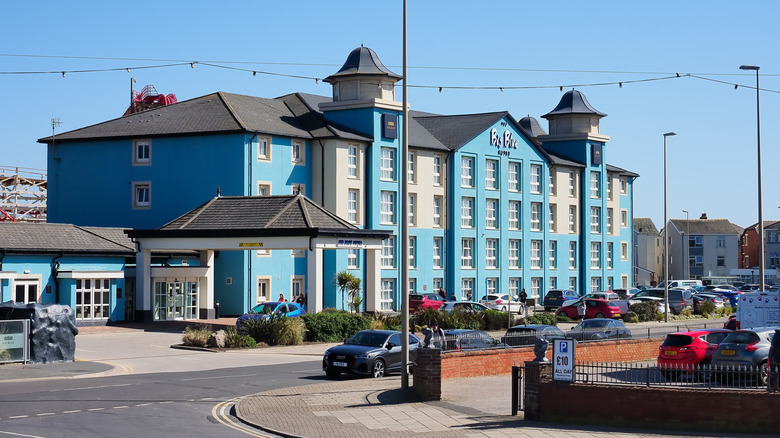 The Big blue hotel in Blackpool with cars parked outside.