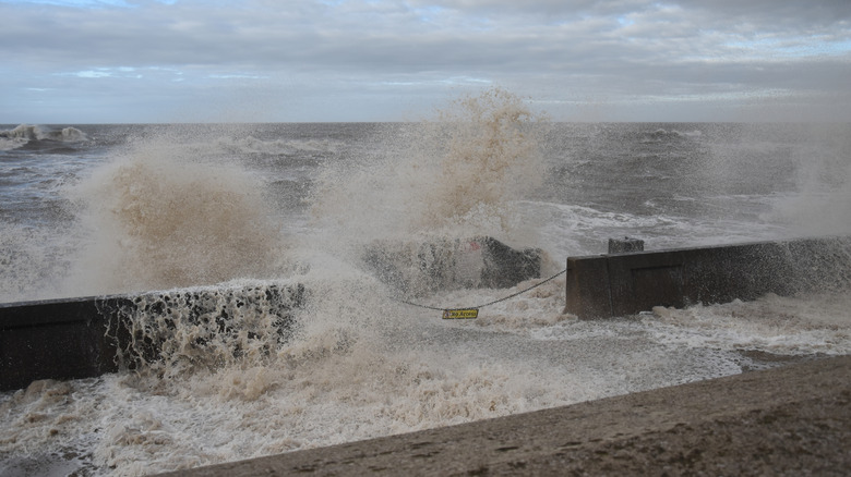 Huge waves crashing over the sea wall in Blackpool as dark and cloudy skies loom in the background
