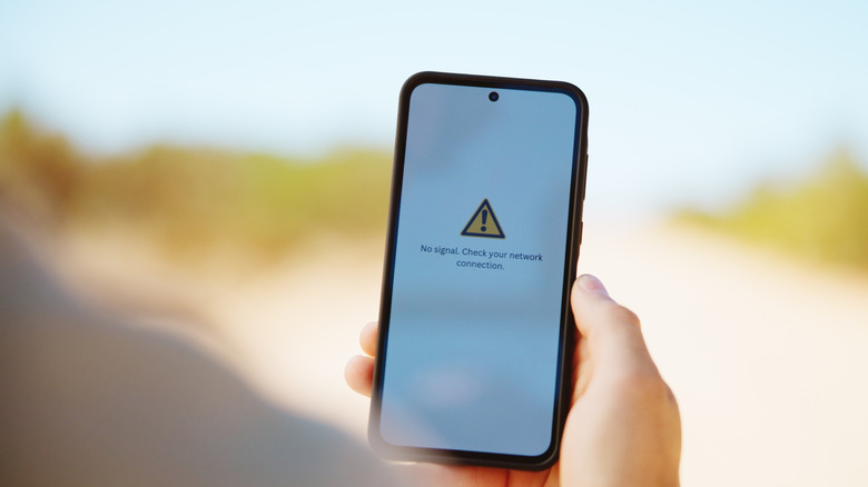 Person, hands, and outdoor background with no signal on phone screen