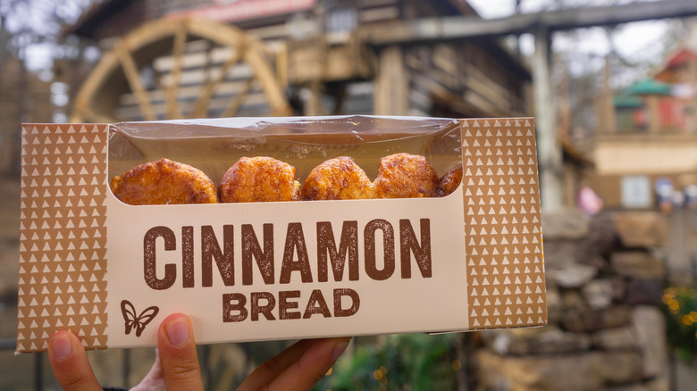 Close view of a hand holding a box of the famous cinnamon bread from Dollywood