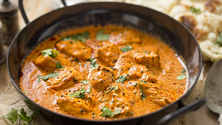 Close up of an Indian chicken dish with naan on the side