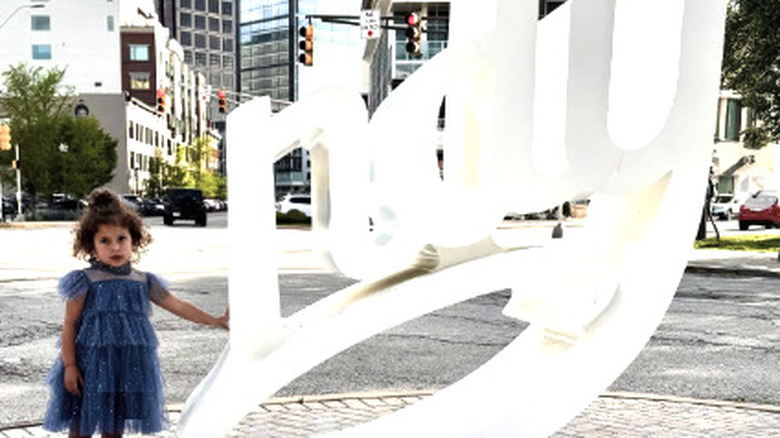 Toddler girl with "Indy" script tourist sign in downtown Indianapolis