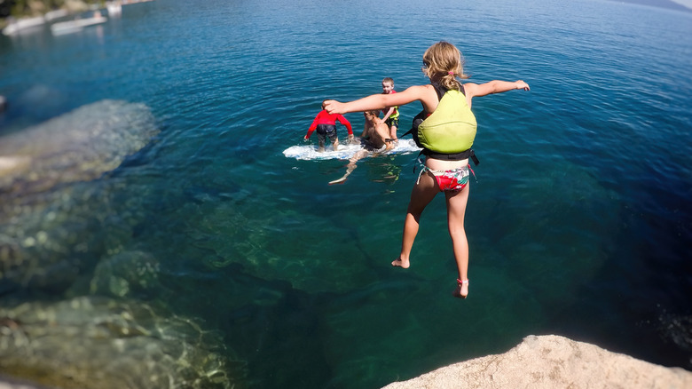 A child wearing a safety vest while jumping into Lake Tahoe