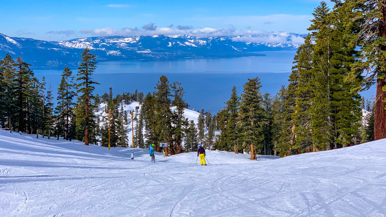 Skiers in the elevated Heavenly ski resort with a view of Lake Tahoe behind