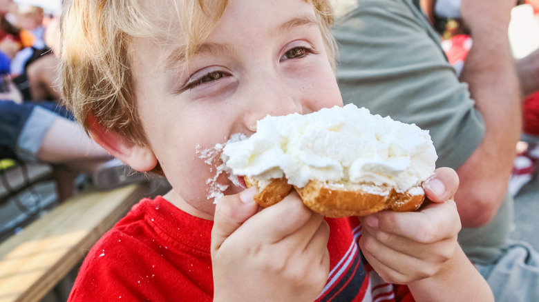 Young boy eating a whipped cream puff pastry at the Wisconsin State Fair