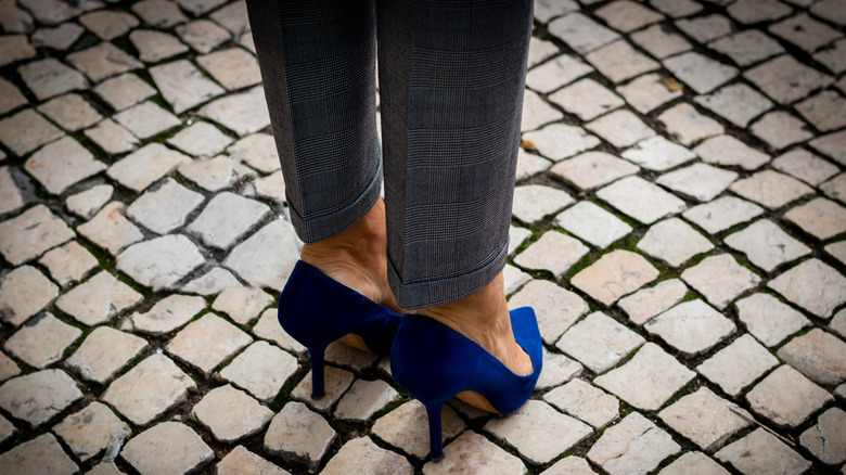 Woman in stiletto heels standing on a cobblestone street