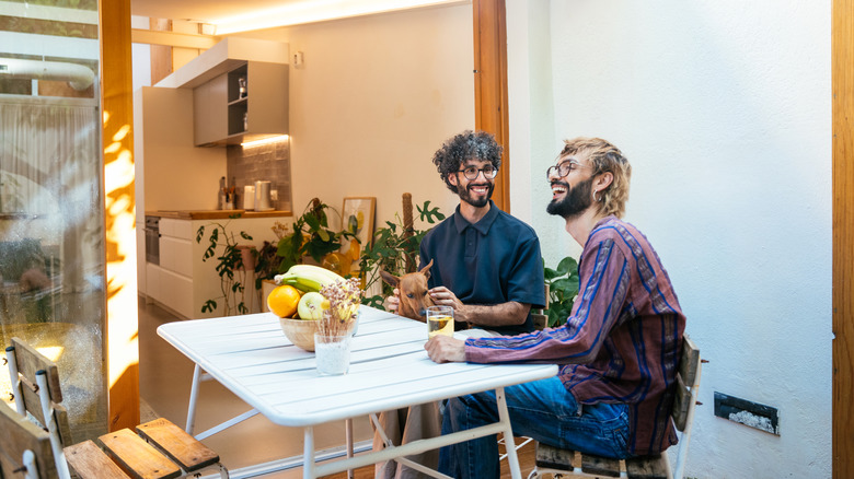 Man holding glass of white wine smiling indoors with friend