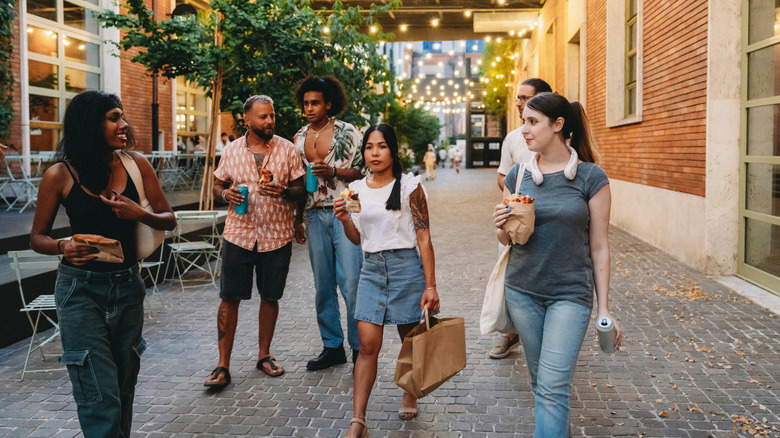 Young adults enjoying street food while walking and socializing in Lisbon