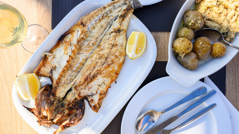 Traditional grilled fish on table beside a fishing harbor on coast of Setúbal, Portugal