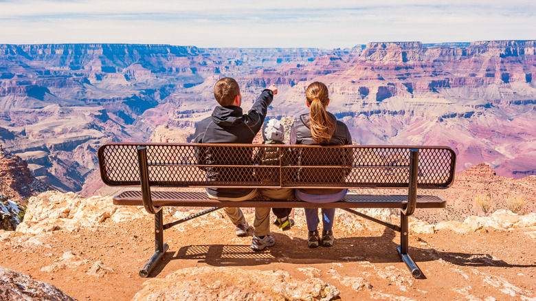 A family sits on a bench overlooking the Grand Canyon